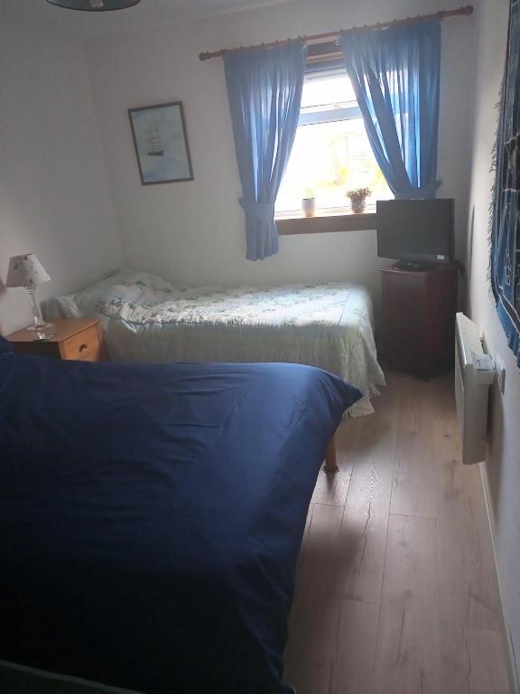 a bedroom with two beds and a window with blue curtains at Rosemarie's B&B in Lochcarron