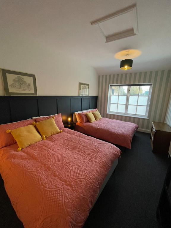 a bedroom with two beds and a window at Old Swan Cottage in Great Massingham