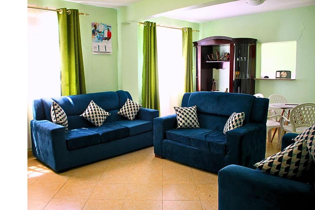 a living room with a blue couch and two chairs at Mamboleo princely Homes in Kisumu
