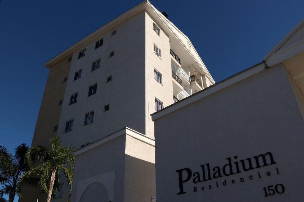 a tall building with a sign in front of it at Curta Praia do Quilombo - Palladium in Penha