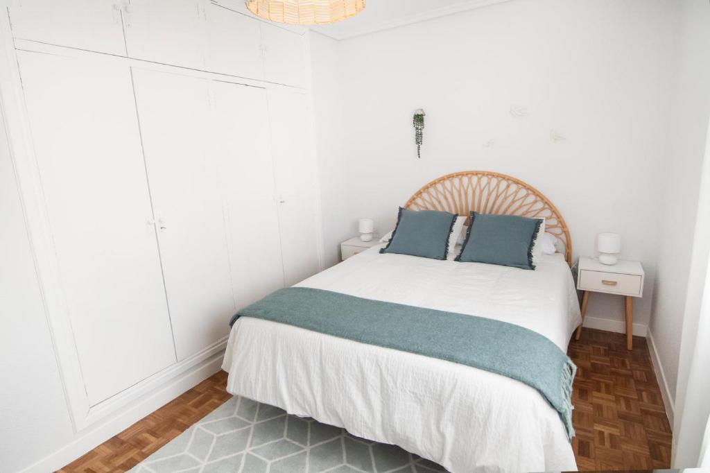 a white bedroom with a bed with blue pillows at Tres Coronas in Olite