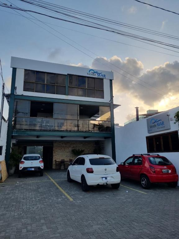two cars parked in a parking lot in front of a building at Verde Mar Pousada in João Pessoa