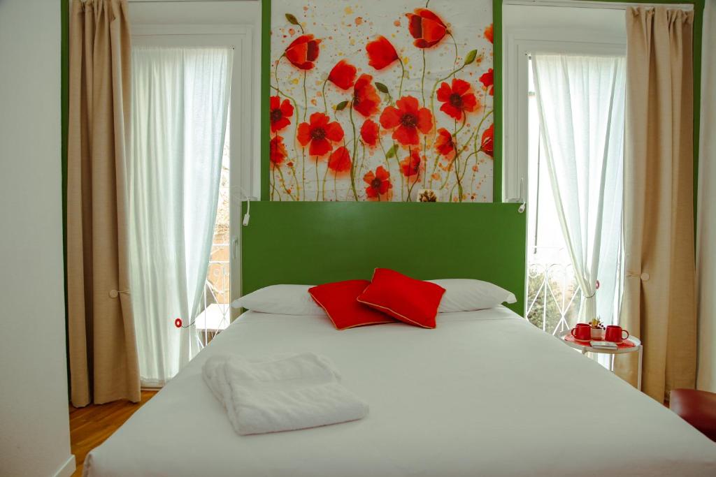a bedroom with a white bed with red pillows at DIMOR'A' ROOMS in Tuscany in Pitigliano