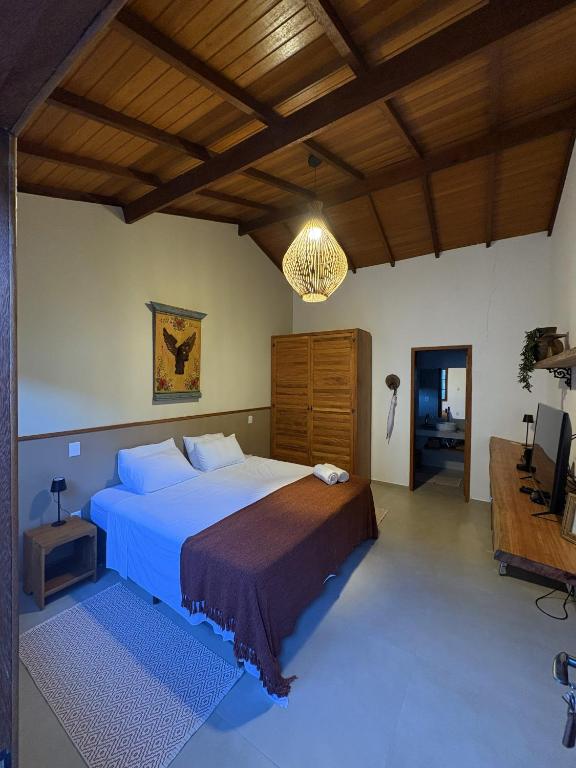a bedroom with a large bed and a chandelier at Vilarejo Ibitipoca in Conceição da Ibitipoca