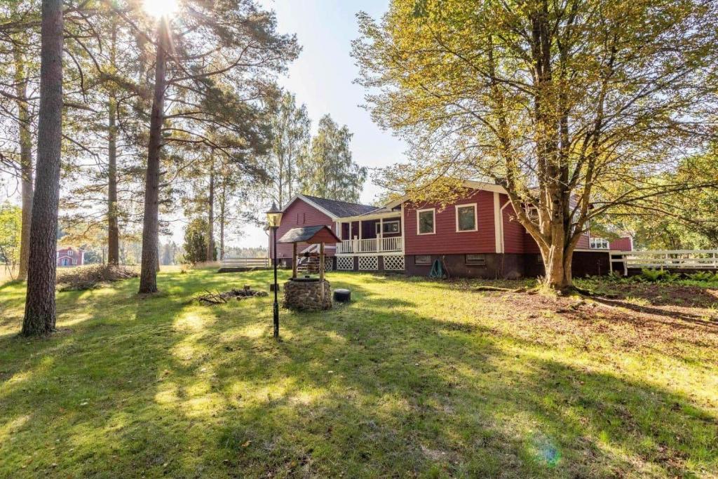 a red house with trees in the yard at KRO906-Lidhult-Torseryd-4 in Lidhult