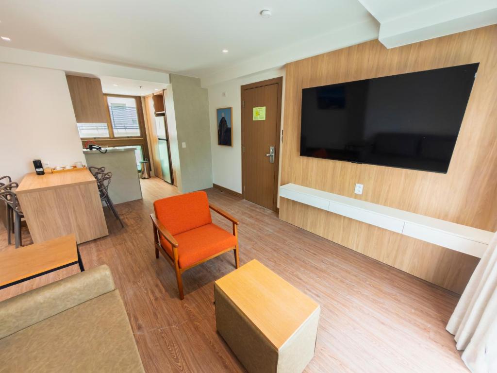 a living room with a large television on a wall at Anna Suites Arpoador in Rio de Janeiro