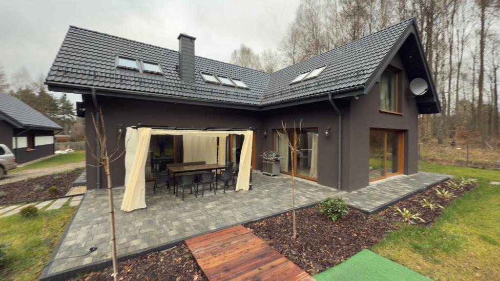 a small house with a patio with a table at Apartament Cisza Leśna in Gołubie