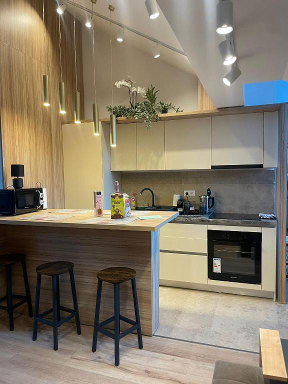 a kitchen with a counter and stools in it at Marova Luxury Loft Caraiman View in Buşteni