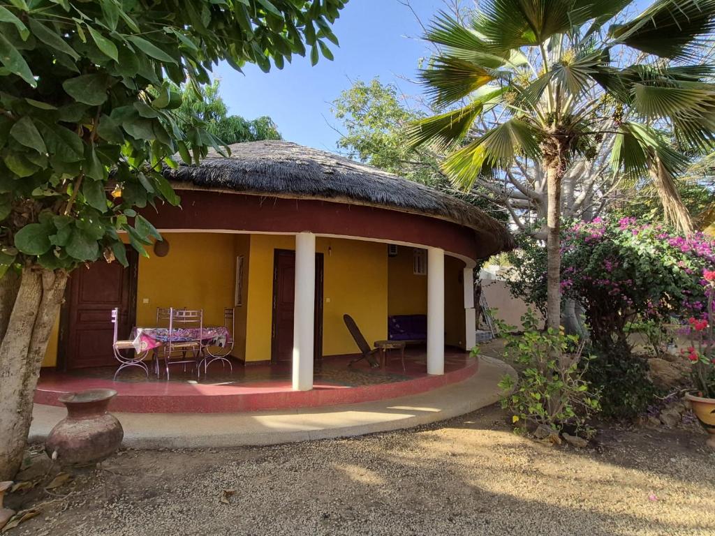 a small yellow house with a thatched roof at keur MaÏ et Mao in Somone