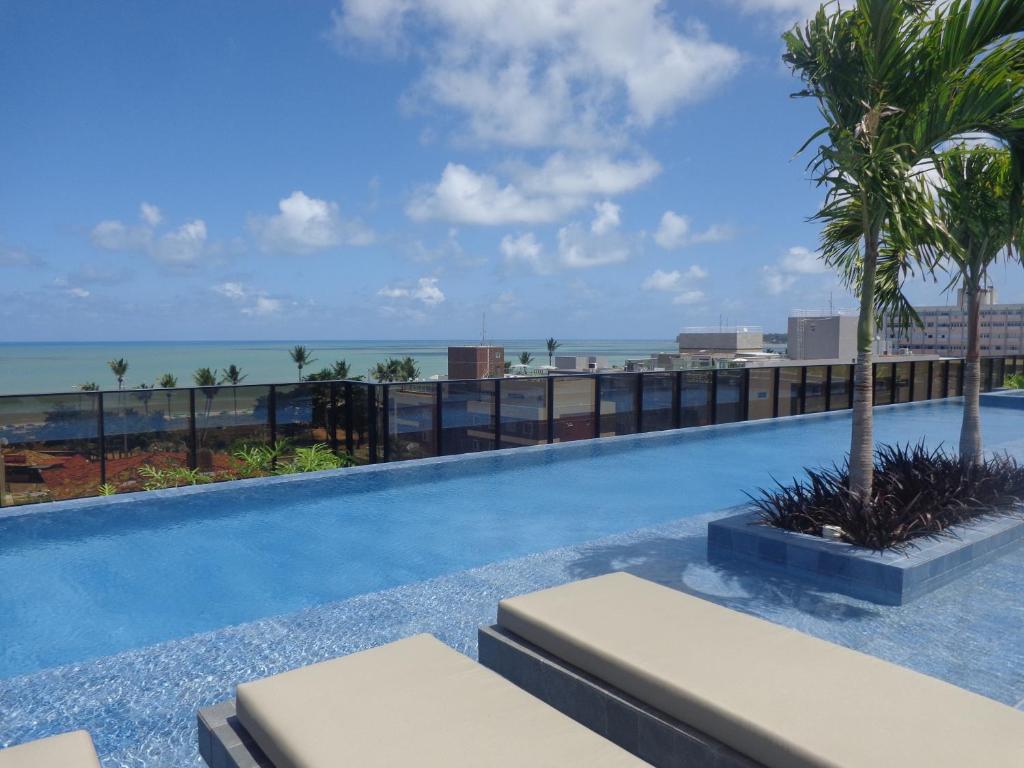 a swimming pool with a view of the ocean at Flat Hit Cabo Branco in João Pessoa
