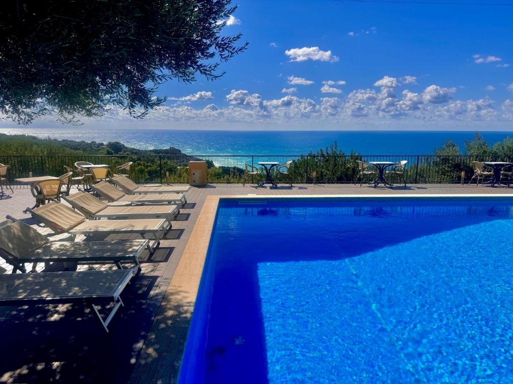 a swimming pool with lounge chairs and the ocean at Villaggio Turistico La Fenosa in Marina di Camerota