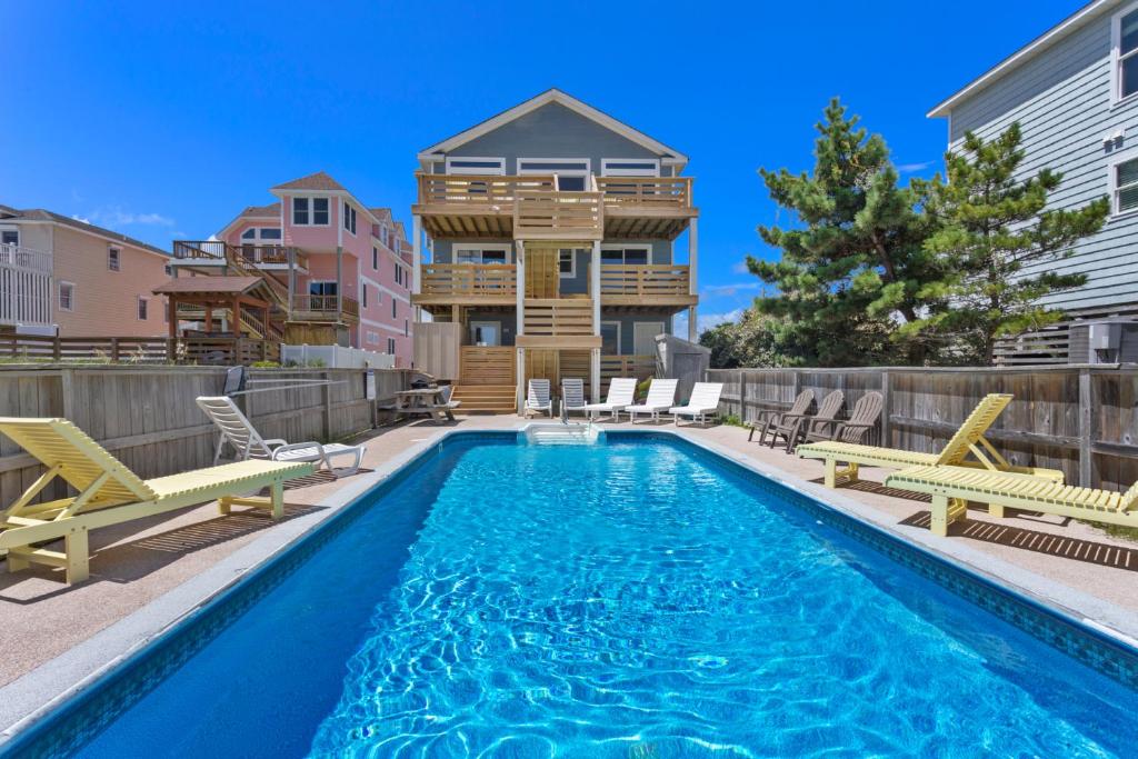 a swimming pool with chairs and a house at 7081 - Southern Breeze in Nags Head
