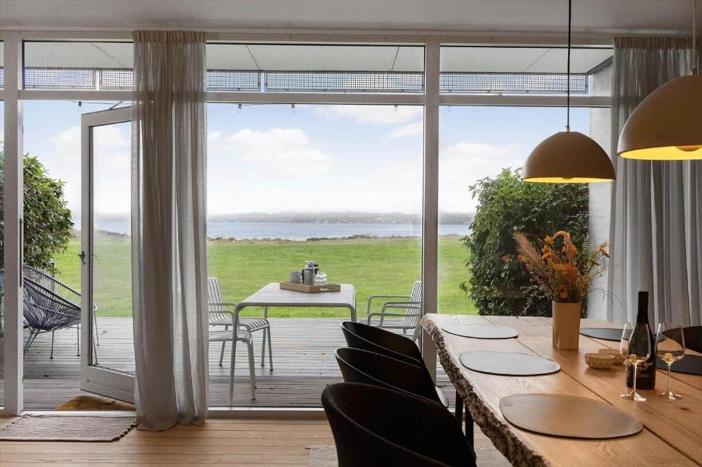 a dining room with a table and chairs and a large window at 84286-Ebeltoft-Ndr-Strandvej-3-M in Ebeltoft