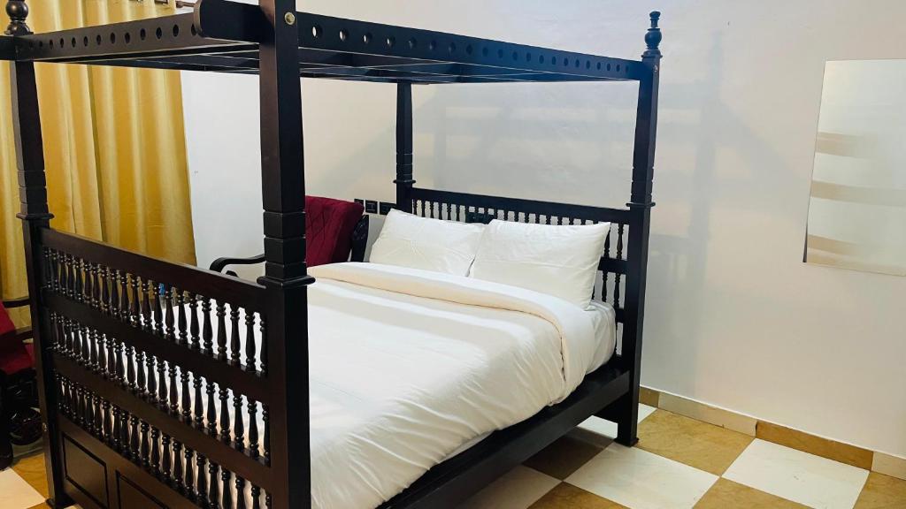 a black canopy bed with white sheets and pillows at Jas Grand Homes in Cochin