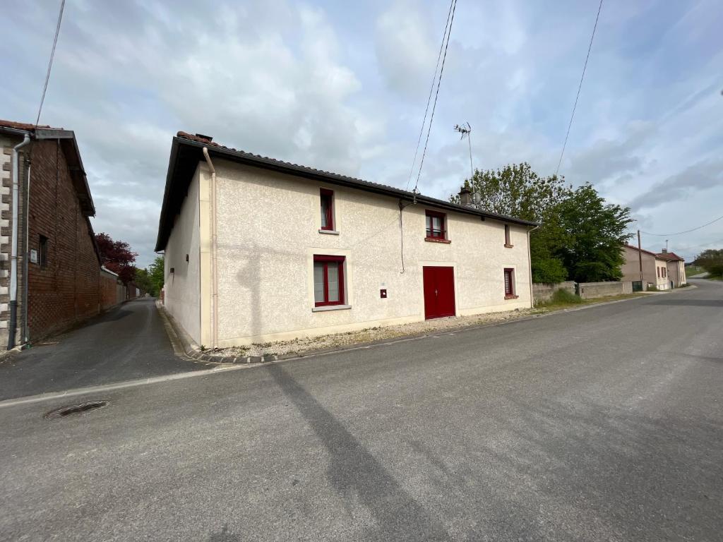a white building with red doors on the side of a street at Maison de Nathony in Maisons-en-Champagne
