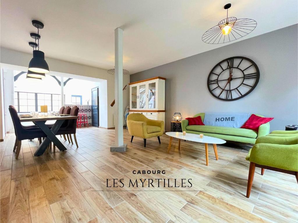 a living room with a table and a clock on the wall at Villa LES MYRTILLES in Cabourg