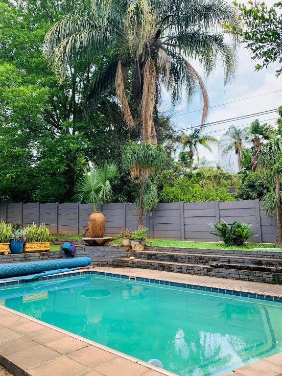 a swimming pool in a yard with a palm tree at The Chalant in Tzaneen