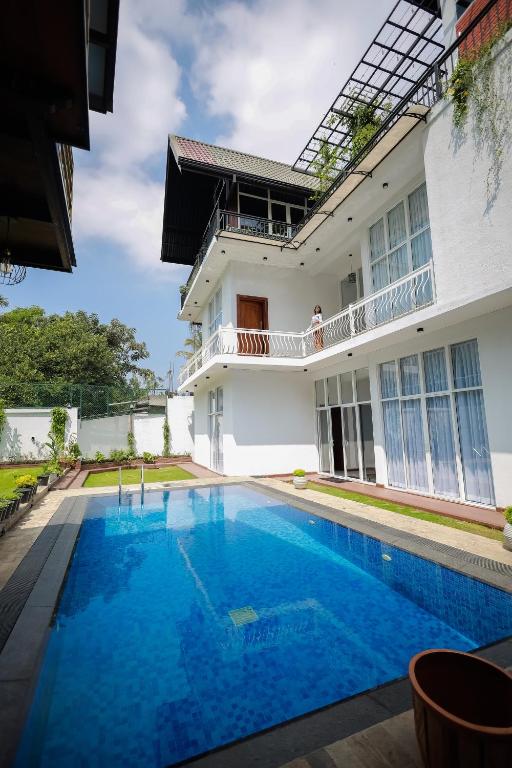 a villa with a swimming pool in front of a house at Yellow Rose Hotel in Kandy