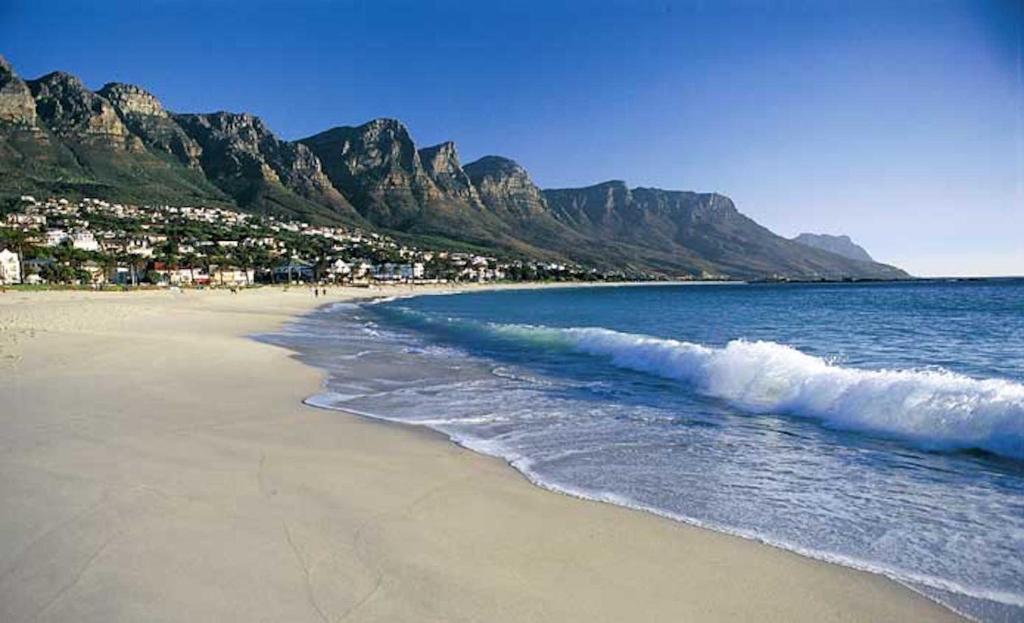 a beach with the ocean and mountains in the background at 15A on Hove in Cape Town