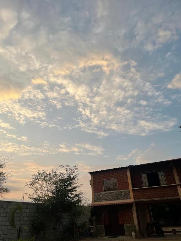 a cloudy sky above a brick building with a house at Raimy Sumaq in Arenillas