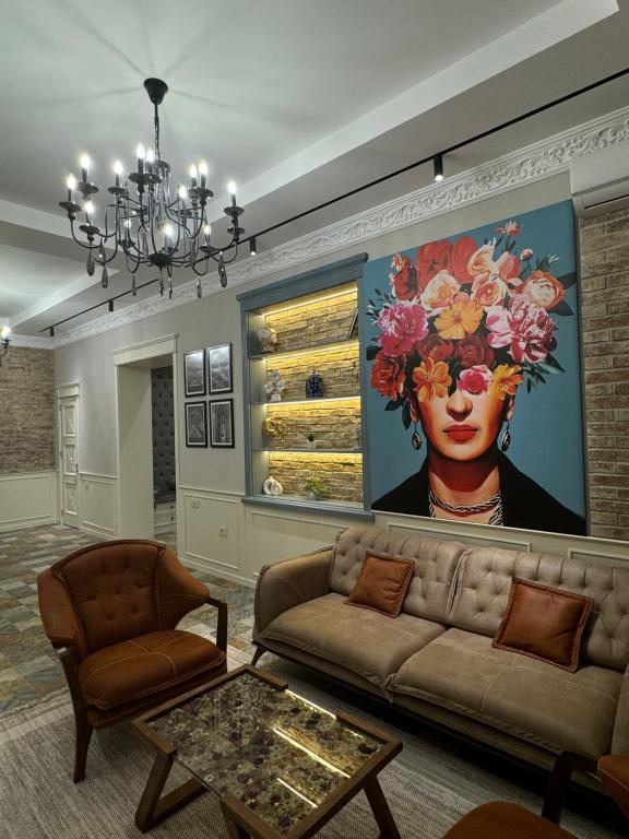 a living room with a couch and a painting of a woman at Bilgeh Old House Villa in Baku
