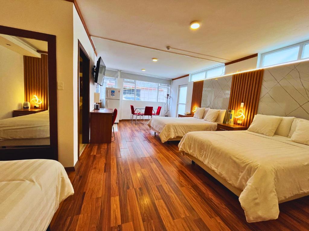 a hotel room with two beds and a television at Casa Hidalgo Ecuador in Cumbayá