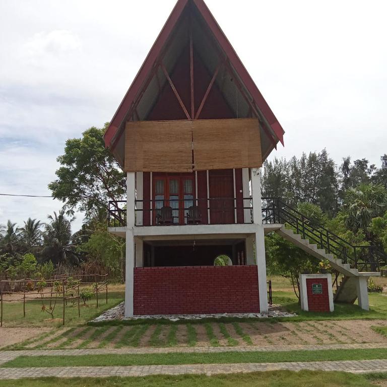 a small building with a staircase in a field at The Corel Waves Inn in Kalkudah