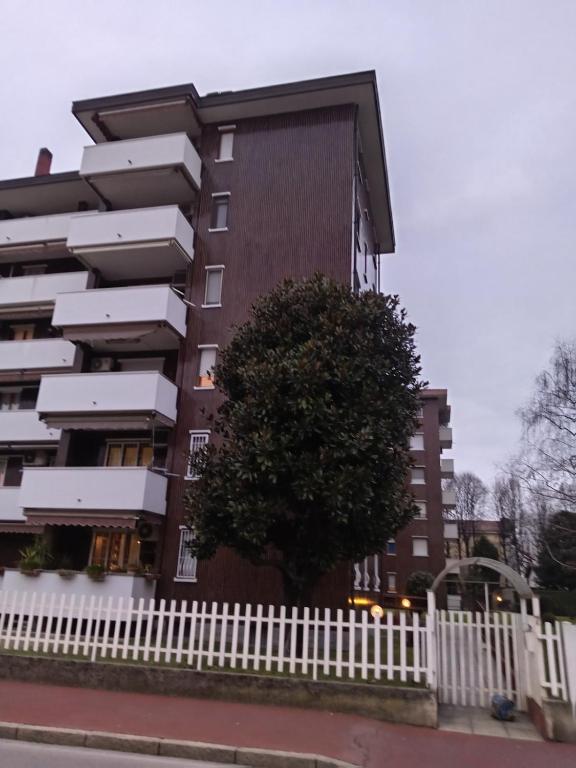 a building with a tree next to a white fence at Lo Studio in Pioltello