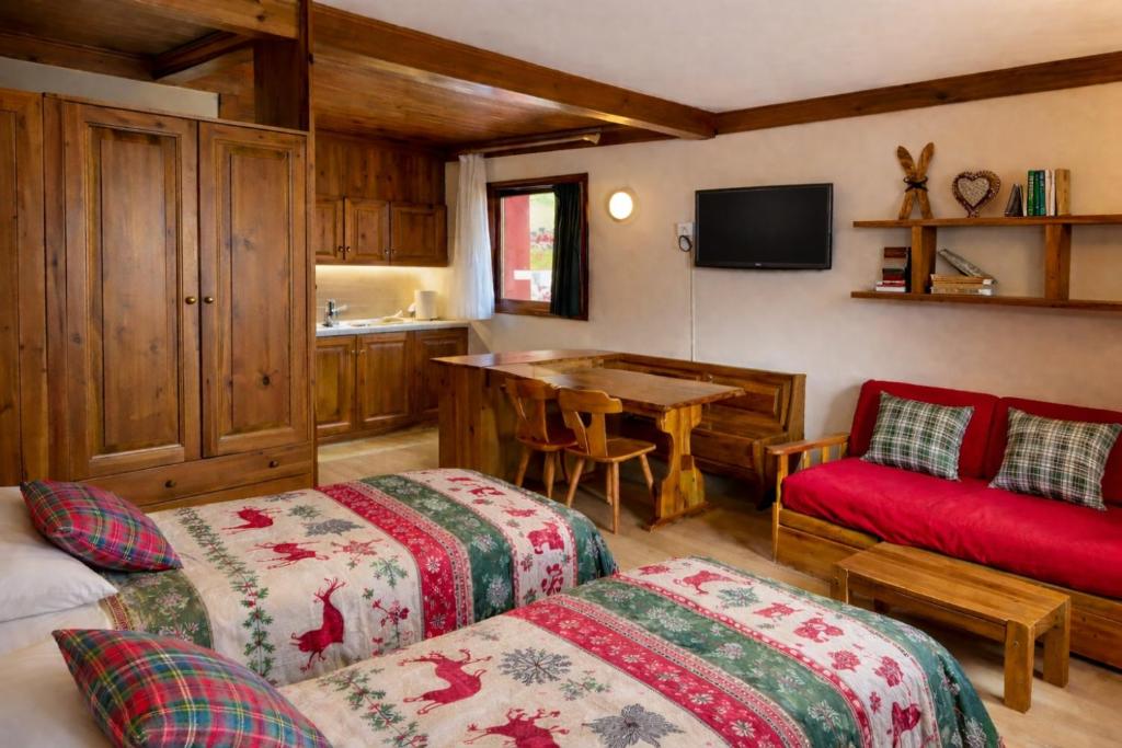 a room with two beds and a kitchen with a table at Chalet Scoiattolo Residence Sussy in Falcade