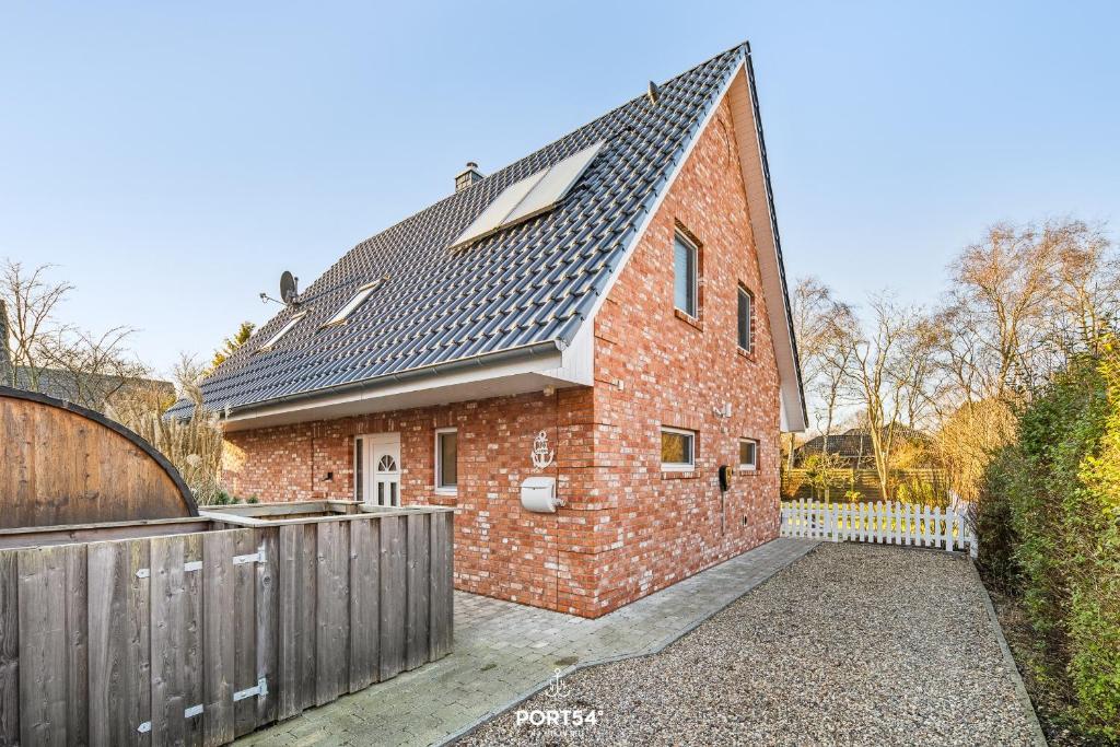 a brick house with a metal roof and a fence at Ferienhaus Ankerplatz St Peter-Ording in Böhl