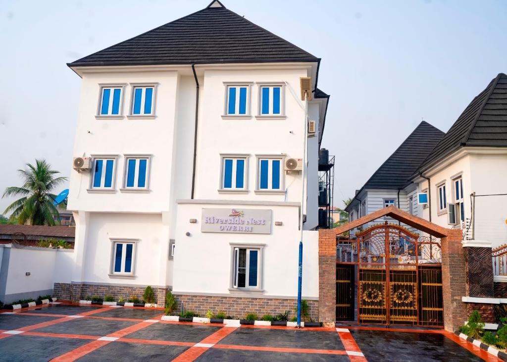 a large white building with blue windows at Riverside Nest Owerri Ltd in Owerri