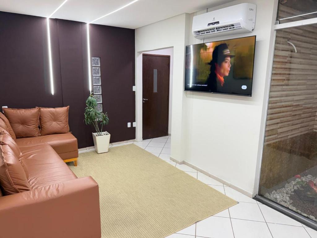 a living room with a couch and a tv on a wall at Hotel Portal do Sertao in Feira de Santana