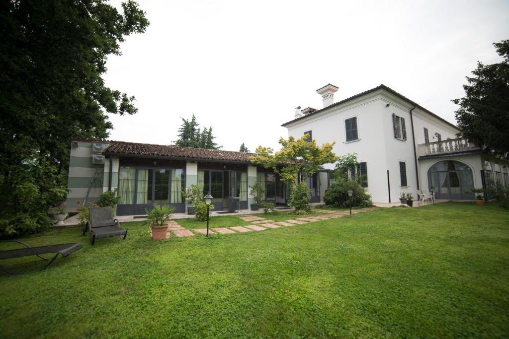 una grande casa bianca con un prato di Villa Franca in Franciacorta a Passirano