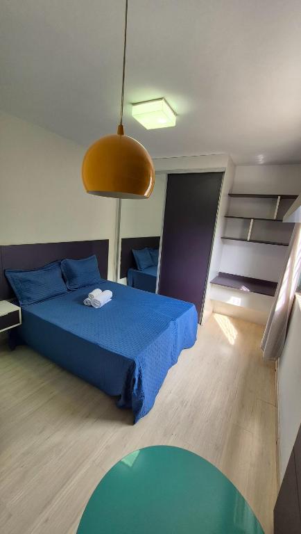 a bedroom with a blue bed and a large light at Pitaia 3 in Aracaju