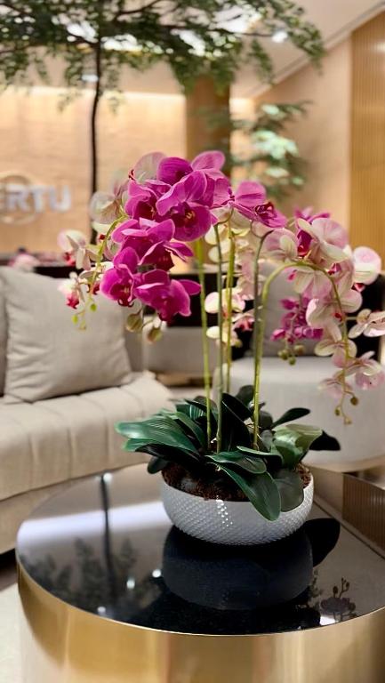 a vase with flowers on a table in a living room at Cozy Studio Unit @Ciputra World Surabaya in Surabaya