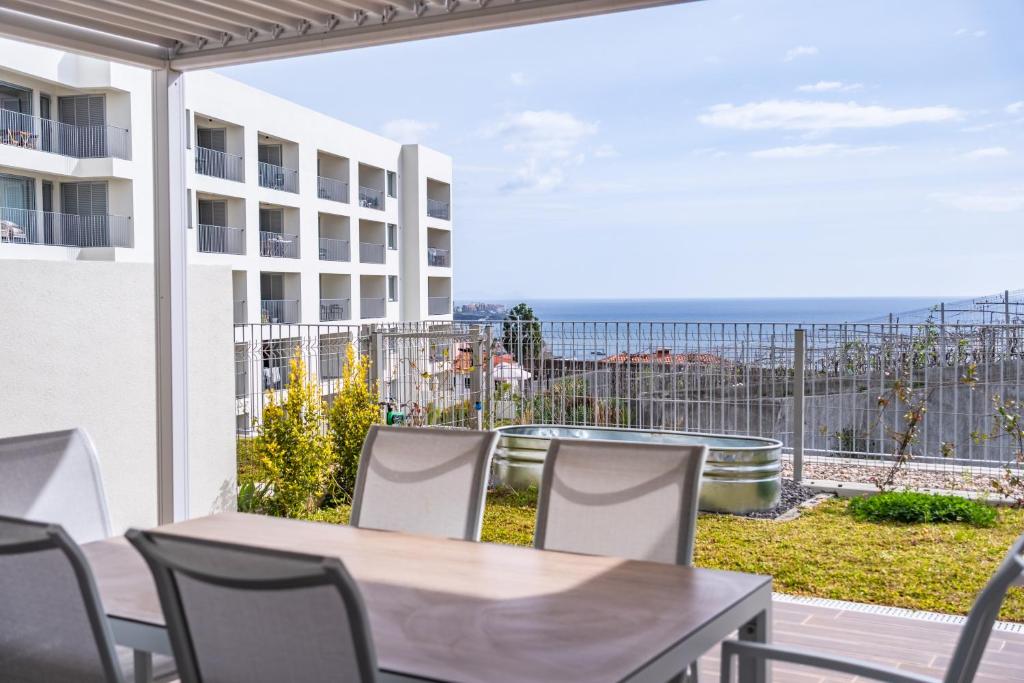 a balcony with a table and chairs and a view of the ocean at Oceanfront Bliss - Atlantico residences in Câmara de Lobos