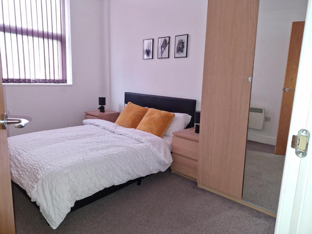 a bedroom with a bed with white sheets and orange pillows at The Cossy Nook in Bolton