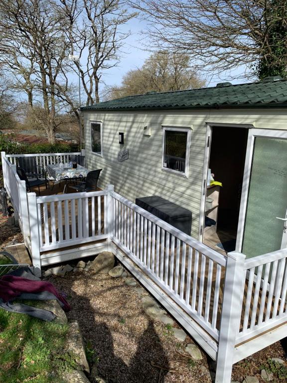 a small house with a porch and a white fence at Park Home in Watchet