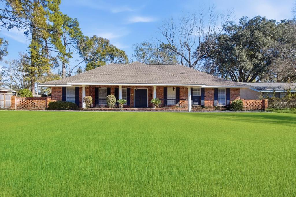 a house with a large lawn in front of it at Rustic Retreat 5-BR Home with Backyard Oasis in Baton Rouge