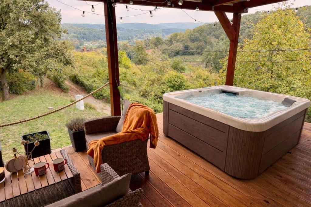 a jacuzzi tub on a deck with a view at Offline vendégház in Orfű