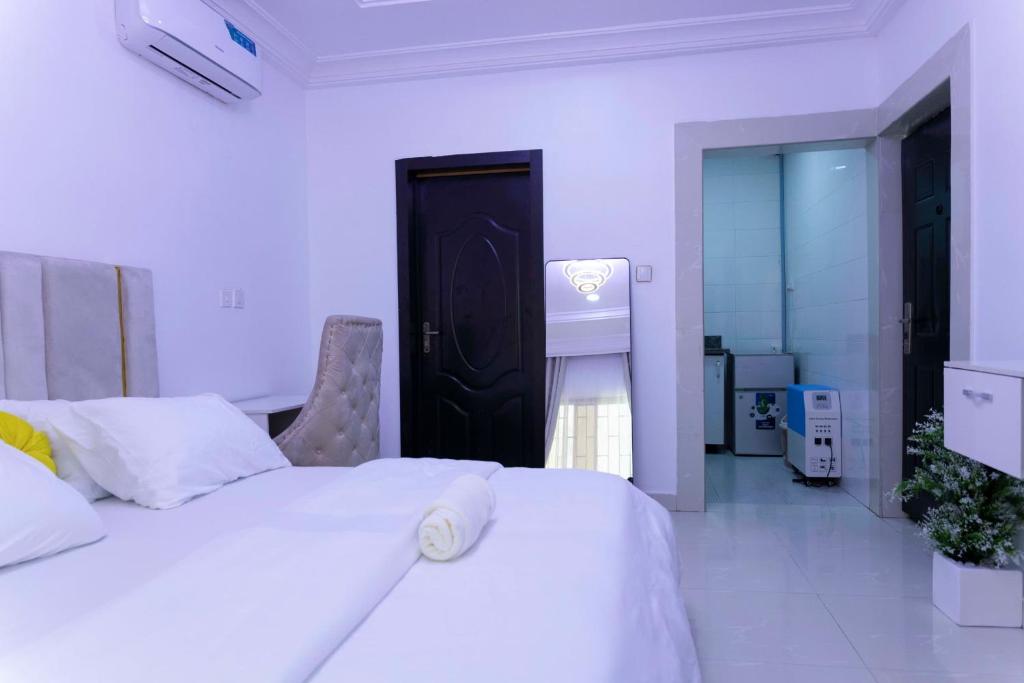 a bedroom with two white beds and a bathroom at Studio apartment GRA IKeja in Ikeja