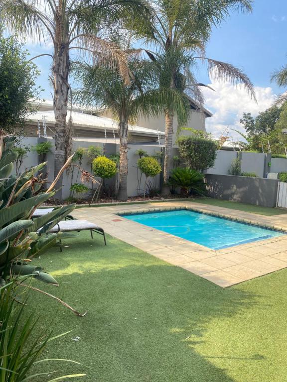 a swimming pool in a yard with palm trees at Andisa Airport Escape in Kempton Park