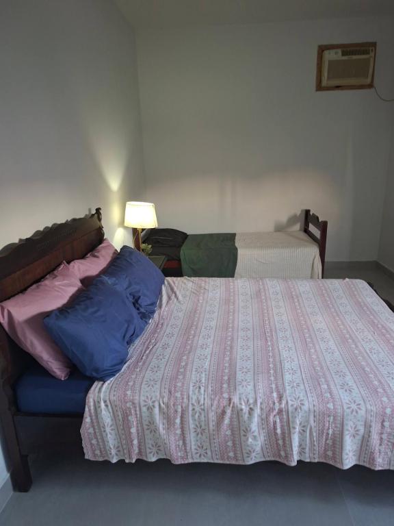 a bedroom with a bed with a pink and blue comforter at Apartamento Brisa do Mar - Casas confortáveis para casal e acompanhantes com garagem in Búzios