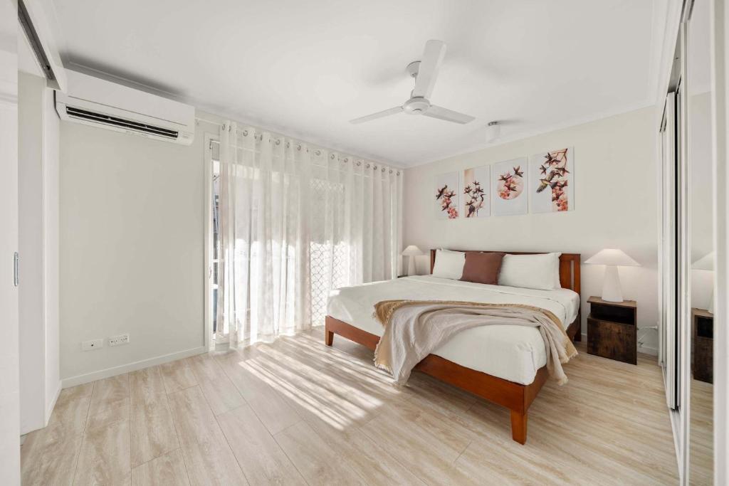 a white bedroom with a bed and a large window at Sunshine Hideaway - Easy Beachside Living in Mooloolaba