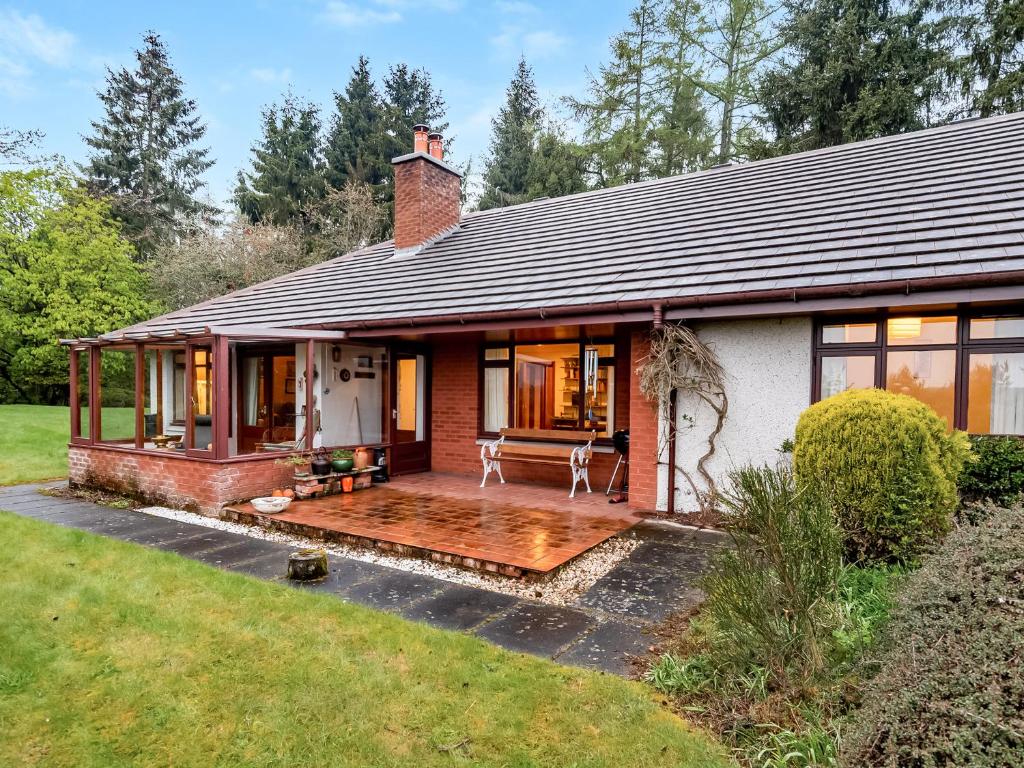 a house with a wooden deck in the yard at Smiddy Cottage in Alyth