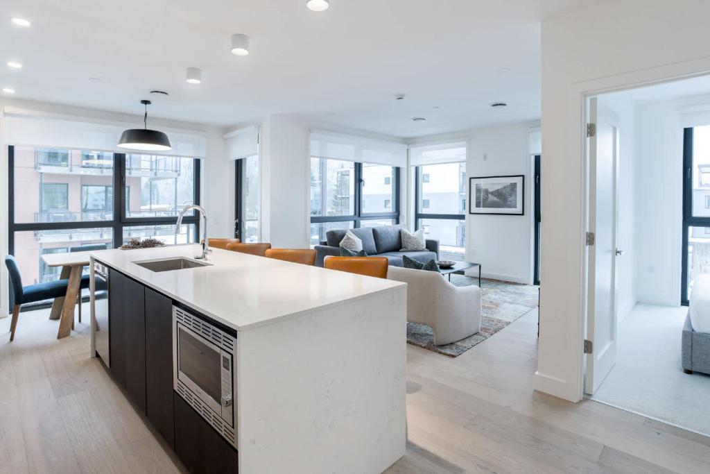 a white kitchen and living room with a couch at Alpine Living - Modern 2 Bedroom Condo in Revelstoke