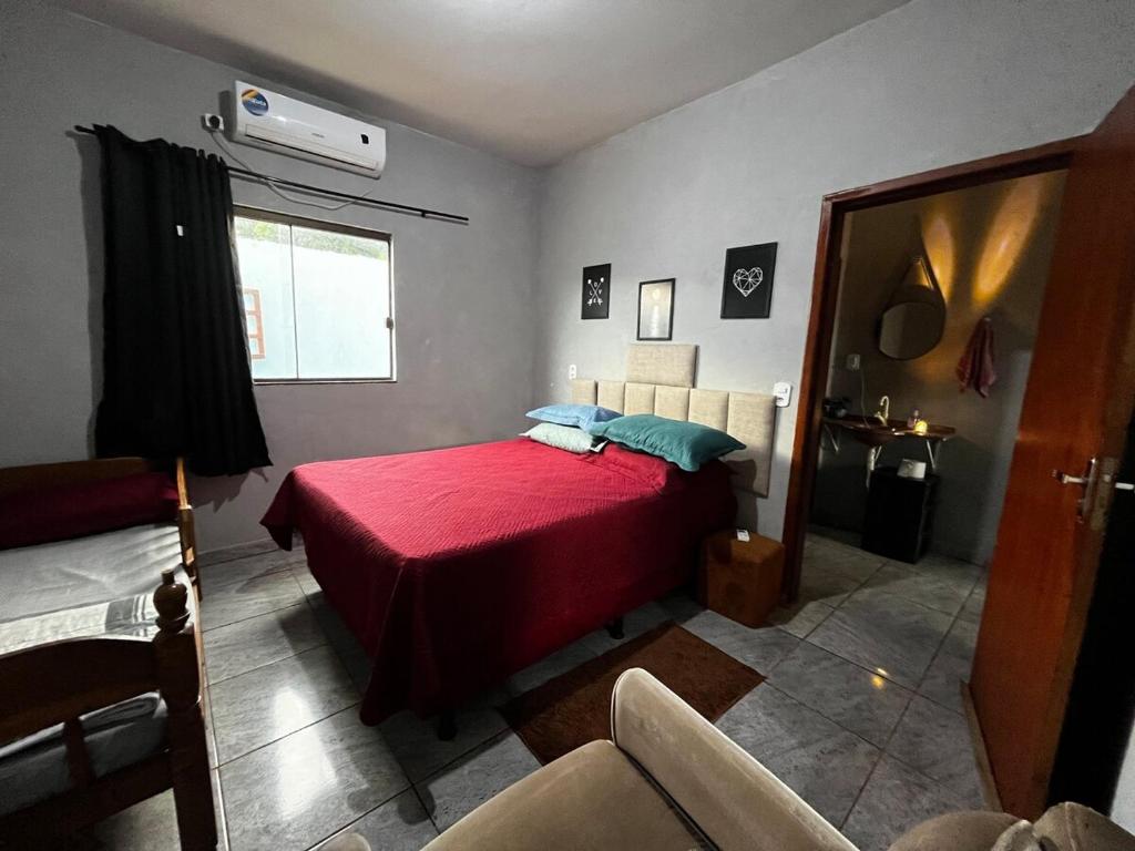 a bedroom with a red bed and a window at Loft B - individual Mobiliado com Ar-condicionado in Dourados