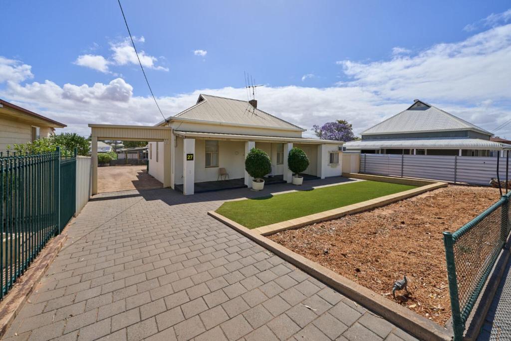 a house with a fence and a driveway at Squatters Cottage in Port Augusta