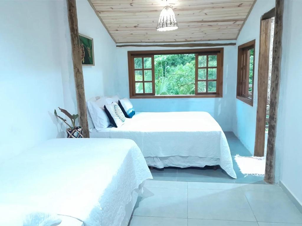 two beds in a room with blue walls and windows at Loft 01 encanto dos ipês in Paraty