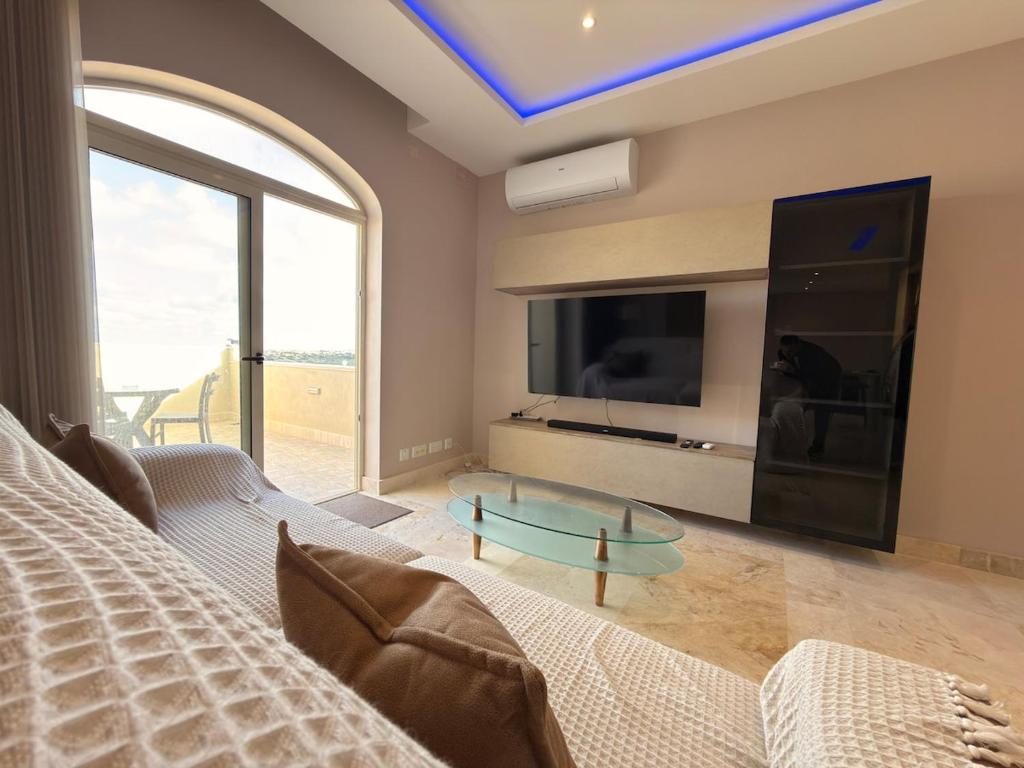 a living room with a couch and a large tv at Panoramic View Penthouse With Dual Terraces in Xagħra